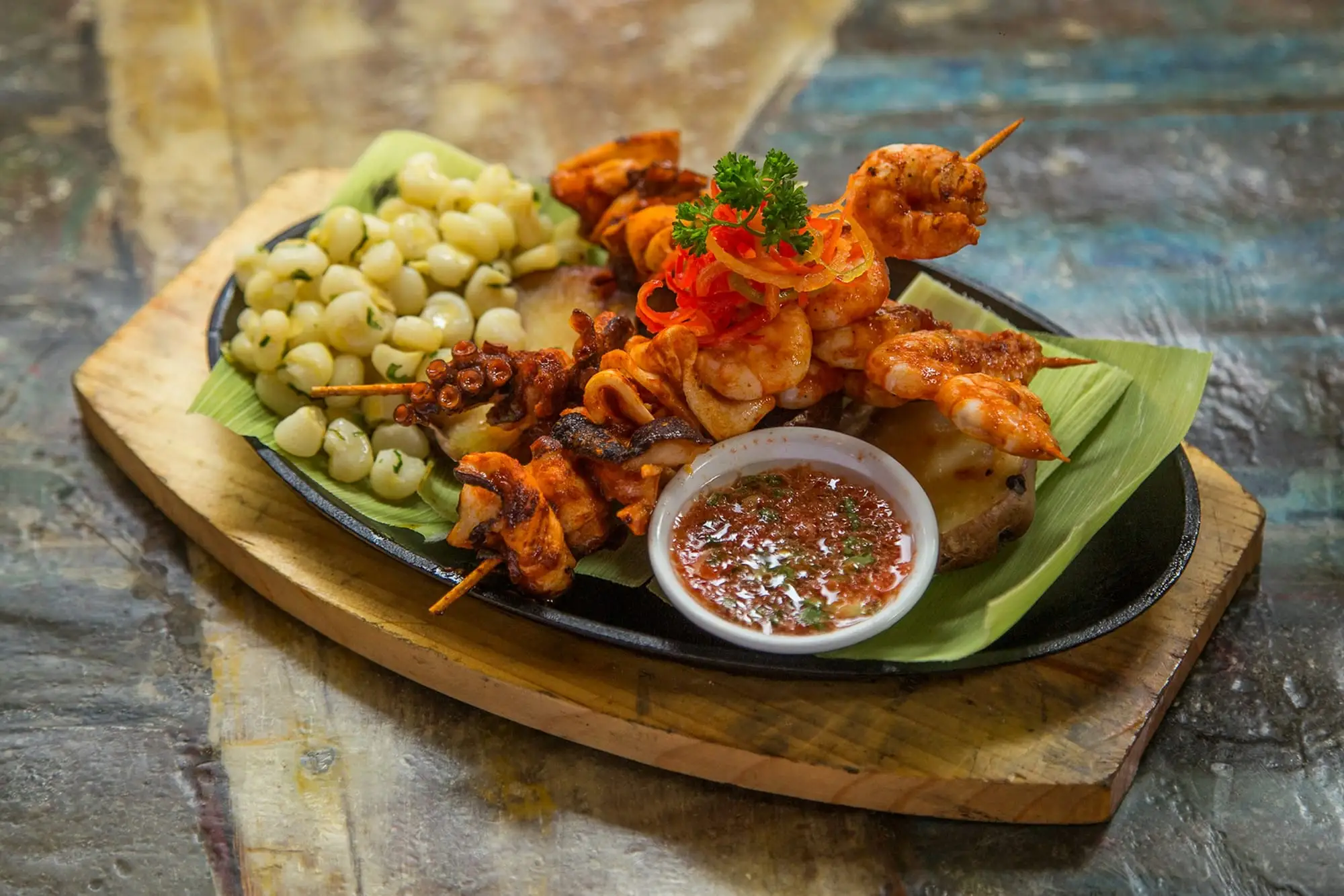 Brochetas de pulpo y langostinos con choclo y salsa de rocoto