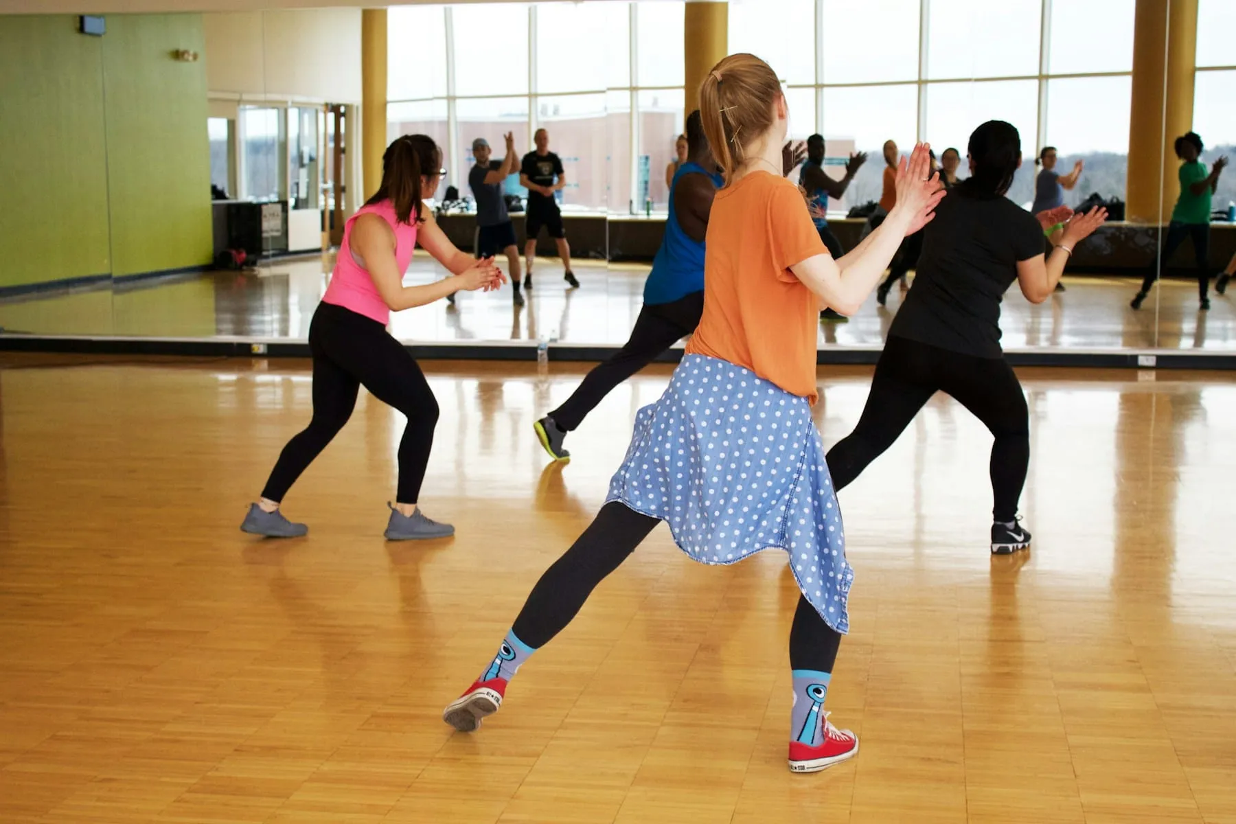 Clase grupal de baile en el estudio, con piso de madera y espejos