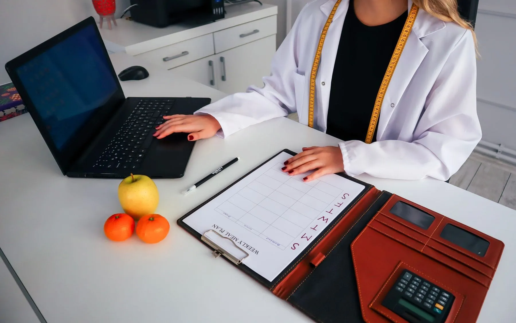 Escritorio de nutricionista con plan alimentario, frutas y computadora
