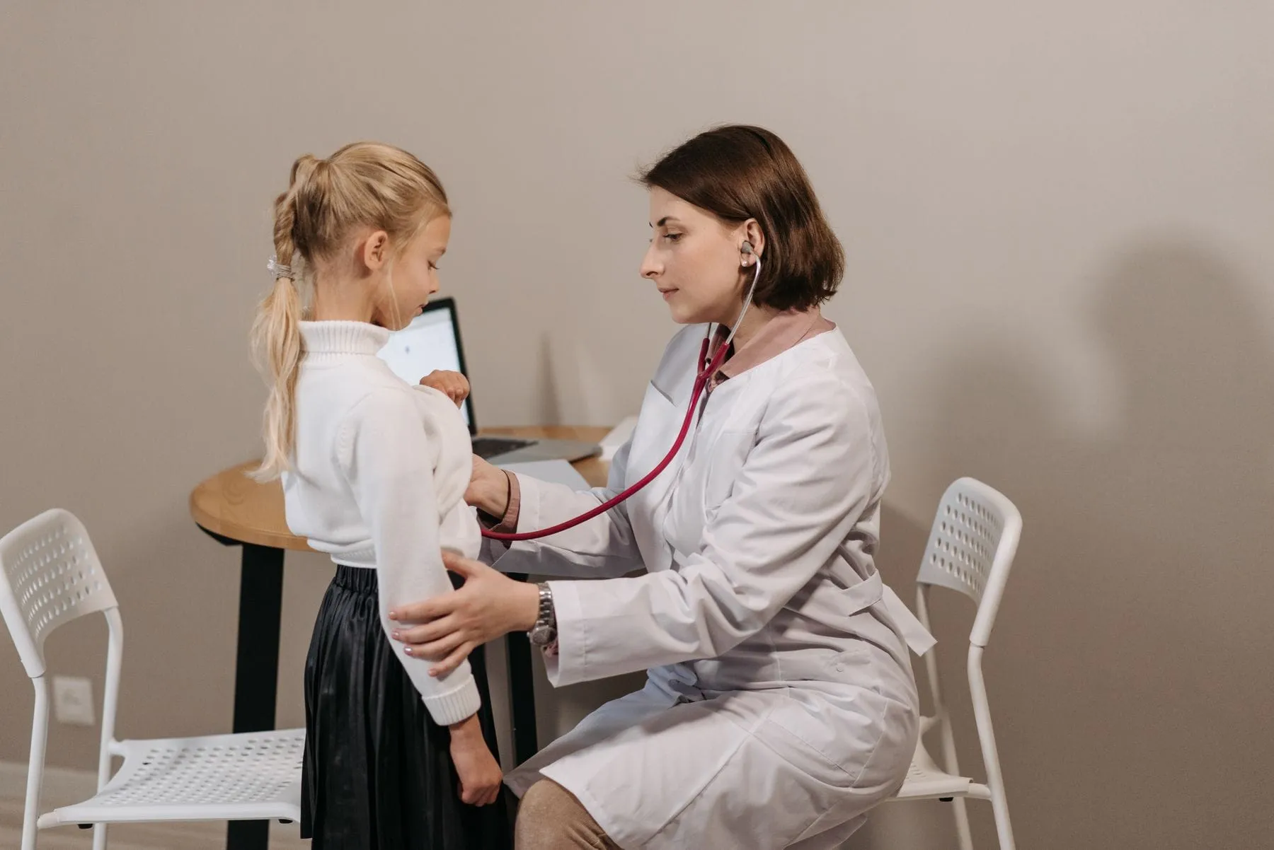 Pediatra revisando a una niña con estetoscopio