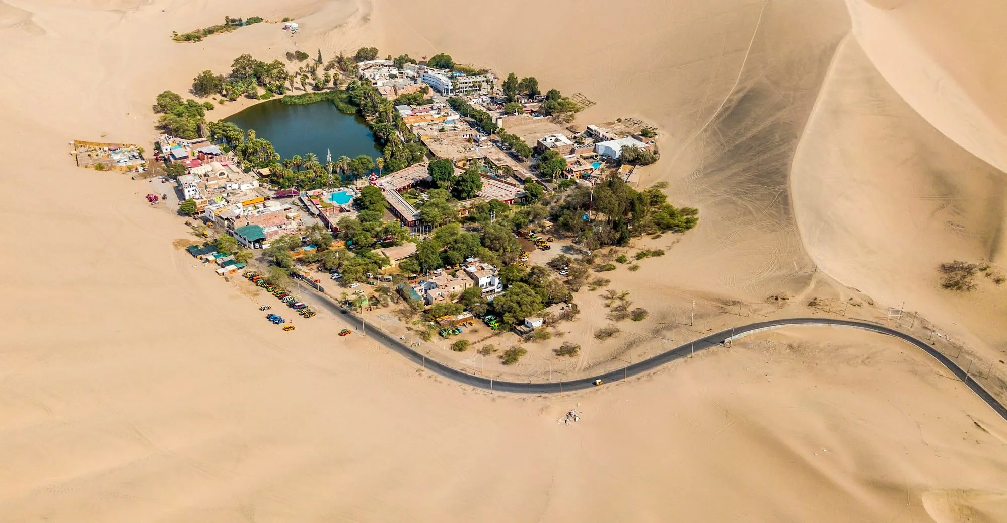 Vista aérea de un oasis rodeado de dunas de arena